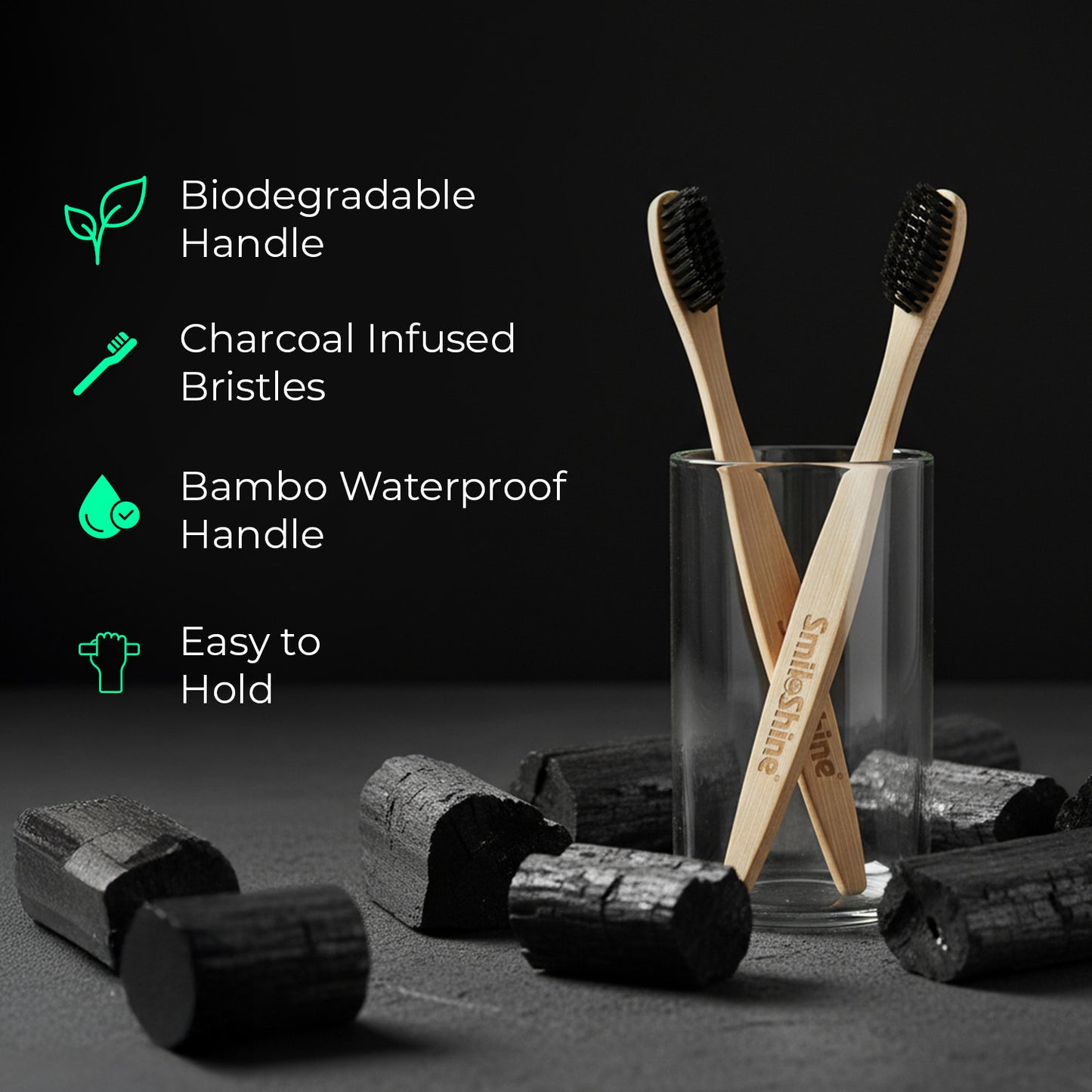 Two SmiloShine eco-friendly bamboo toothbrushes with charcoal-infused bristles and biodegradable handles in a glass holder.